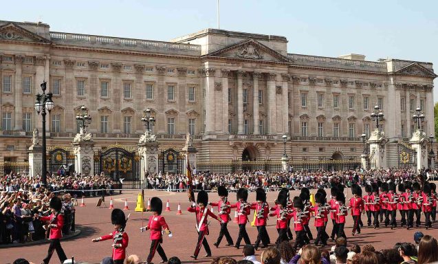 London Charging of the Guard Royal guards in red uniforms parade outside Buckingham Palace with a crowd watching.